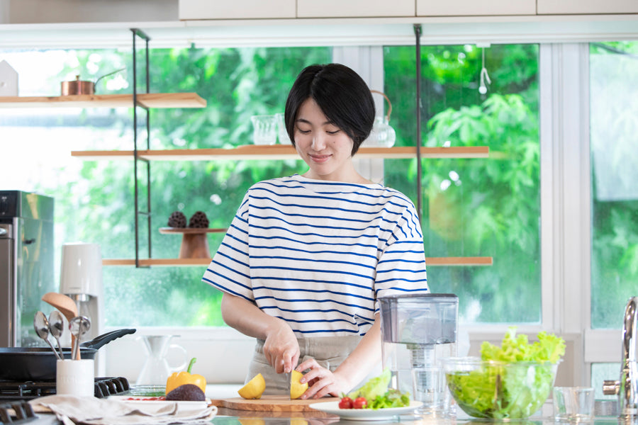 明るいキッチンで、Miz-Uをそばに置いて野菜を切る